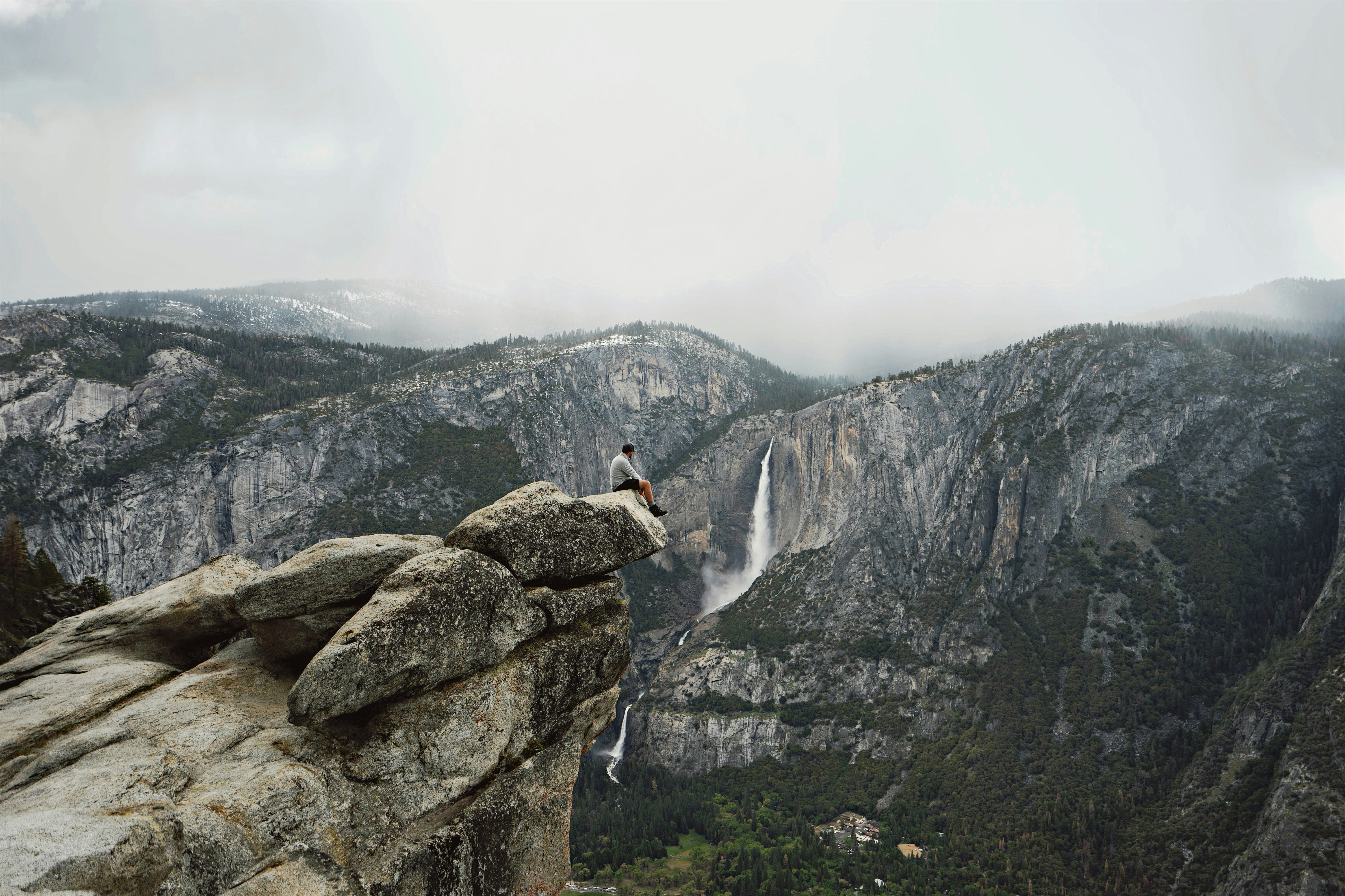 person sitting on mountain cliff